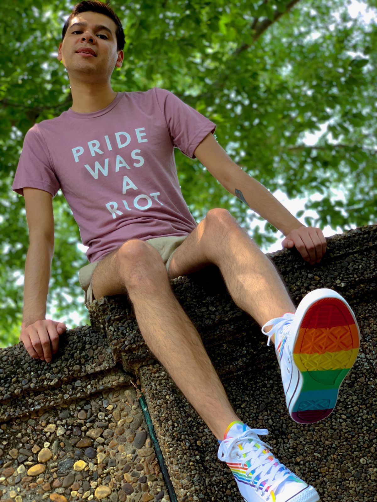 Jose Munoz poses in a T-shirt that says, “Pride was a riot.” The soles of his sneakers are rainbow-colored.