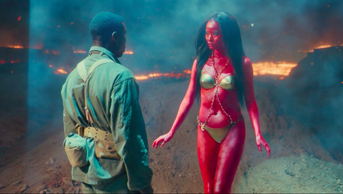 A soldier stands facing a red-skinned woman in a bikini.