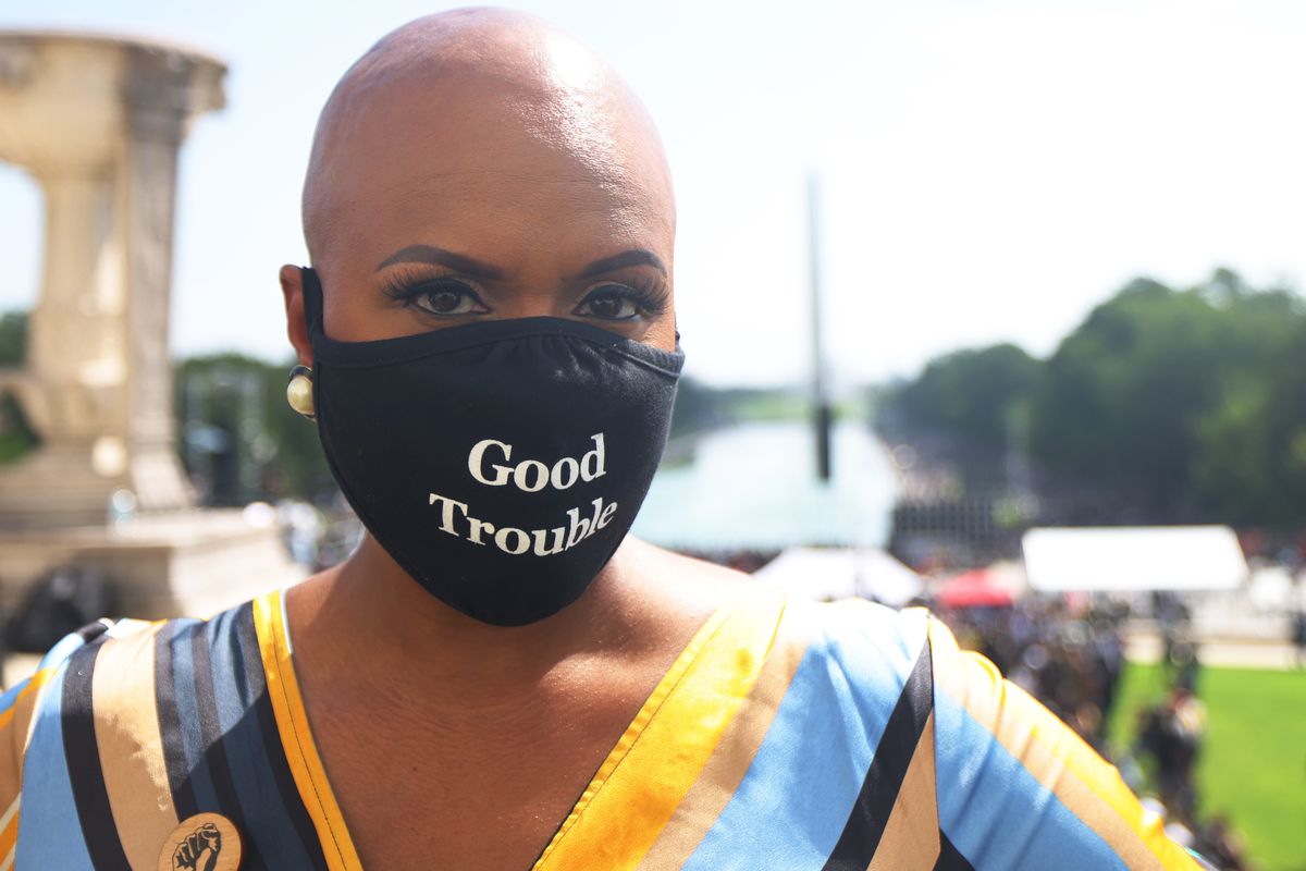 Portrait of Rep. Ayanna Pressley wearing a mask stating “Good Trouble”